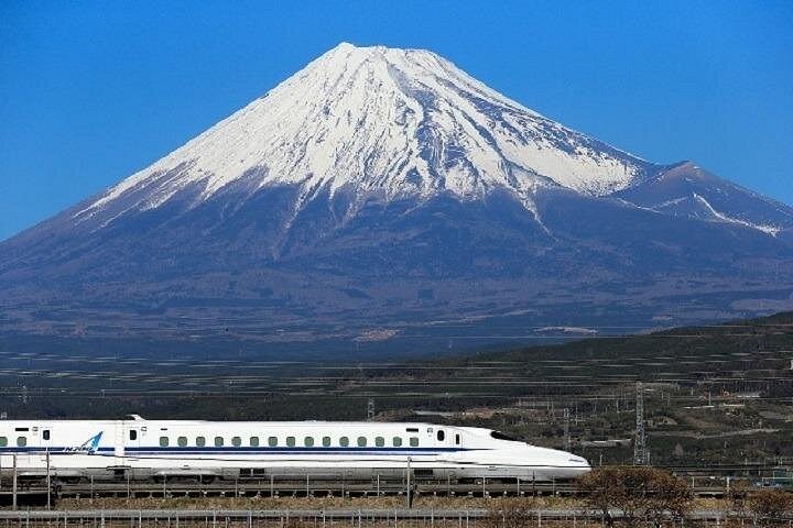 White Shinkansen passing in front of snow-covered Mount Fuji under a clear sky